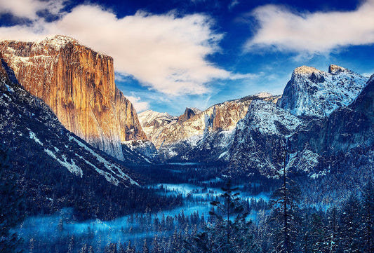 Snow-dusted granite cliffs and a snowy forest on the floor of Yosemite Valley, seen from Tunnel View on a winter morning